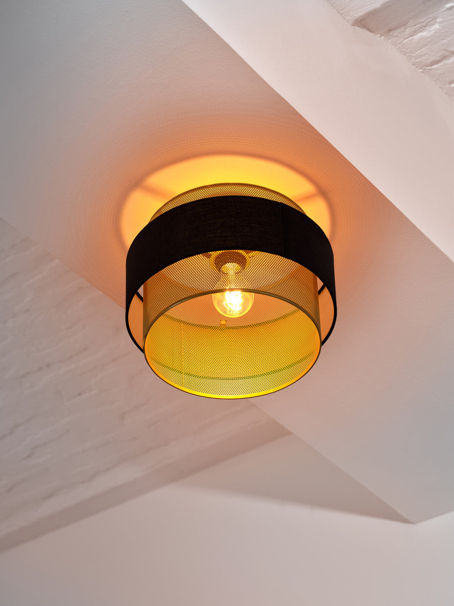 Vue par en-dessous du plafonnier allumé dévoilant l'ampoule et les reflets.