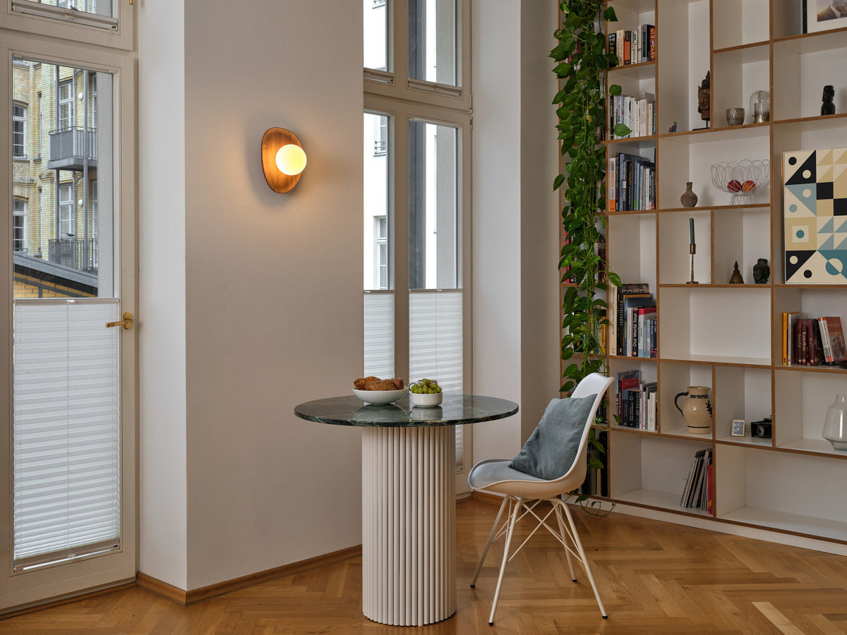 Mise en situation du luminaire mural allumé au-dessus d'une table dans un intérieur moderne.