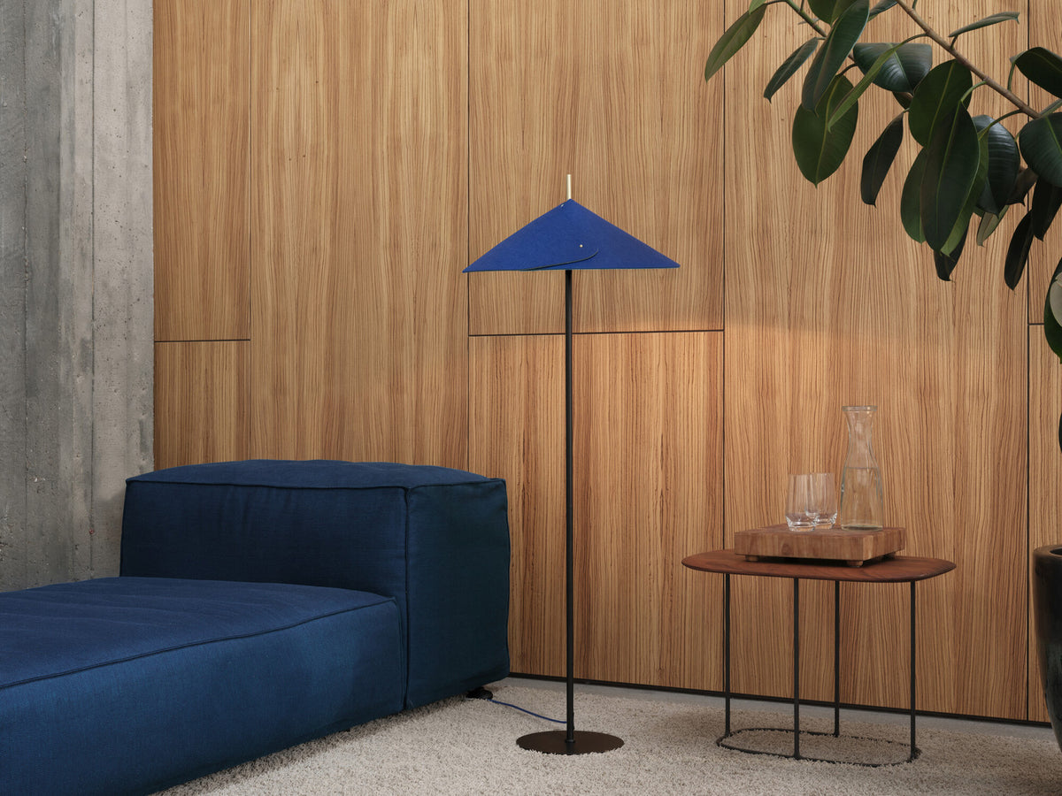 Lampadaire bleu en situation dans un salon, près d'un canapé et d'une table basse.