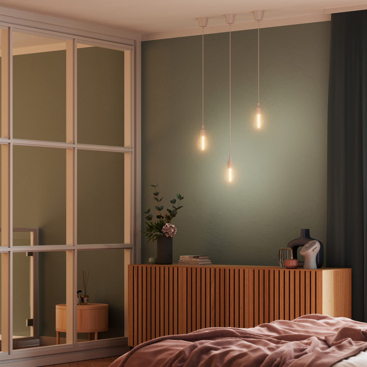 Trois suspensions blanches allumées au-dessus d'un meuble en bois dans une chambre.