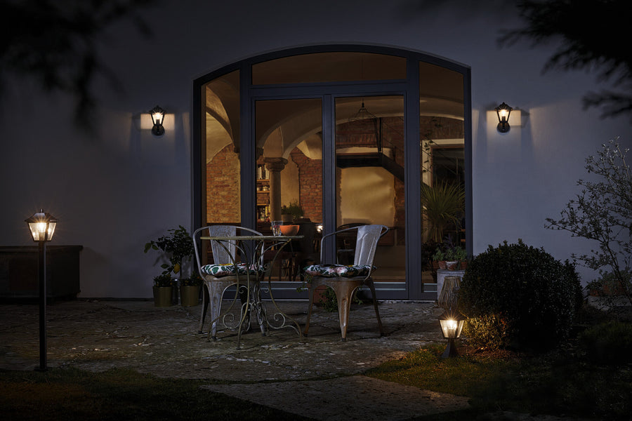 Patio nocturne avec deux appliques murales allumées de part et d'autre de la baie
