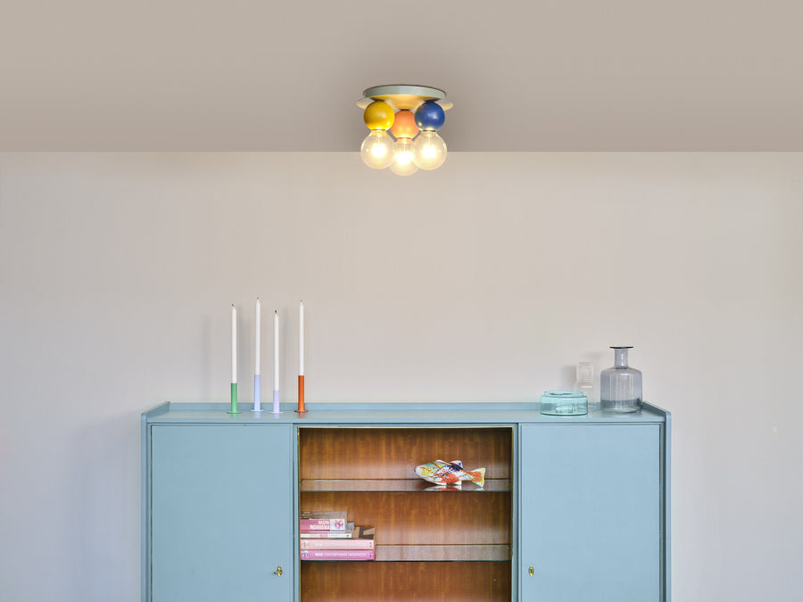Plafonnier allumé au-dessus d'un meuble bleu dans un intérieur clair et minimaliste.