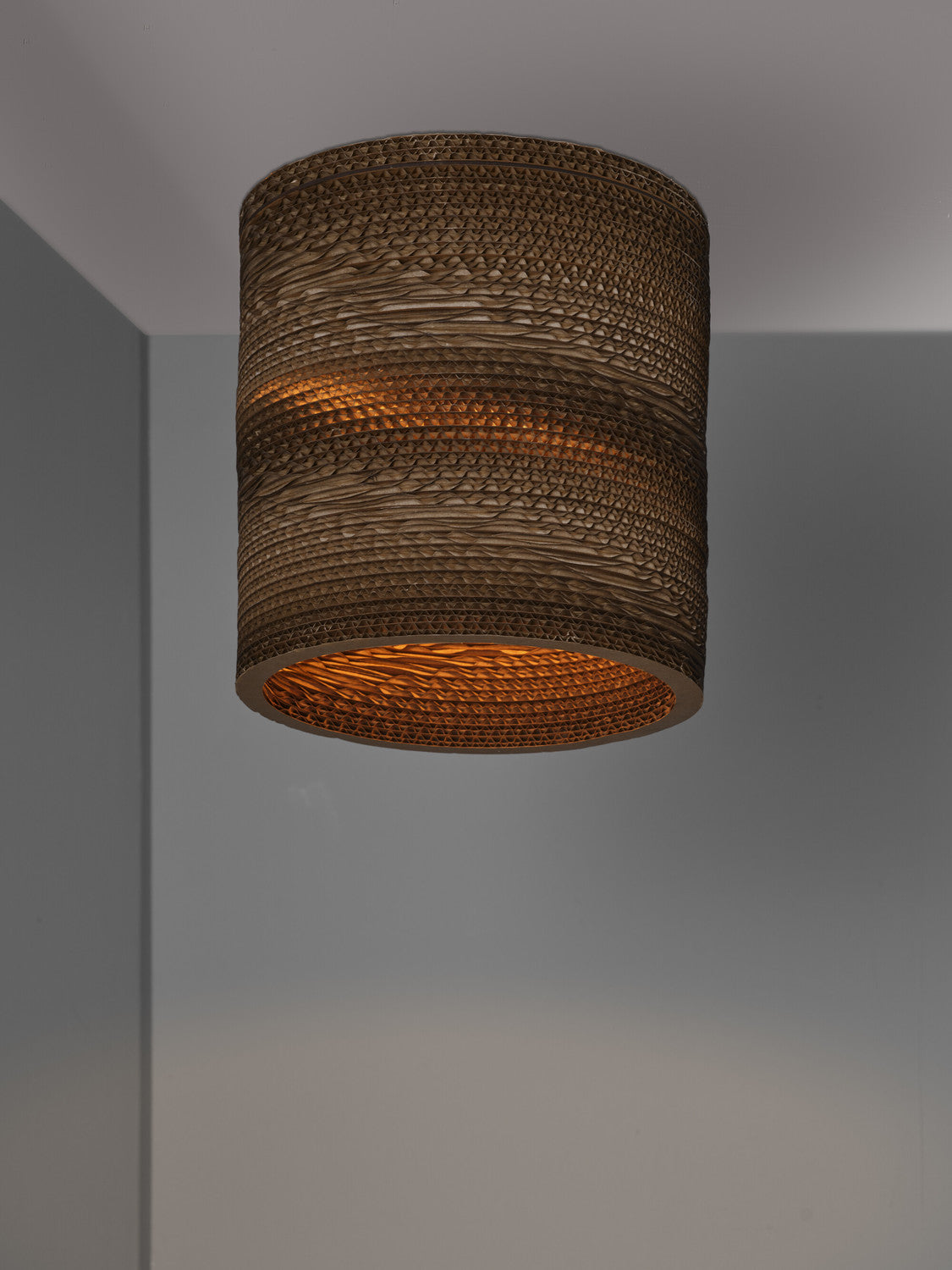 Gros plan du plafonnier fixé au plafond, lumière chaude diffusée vers le bas.