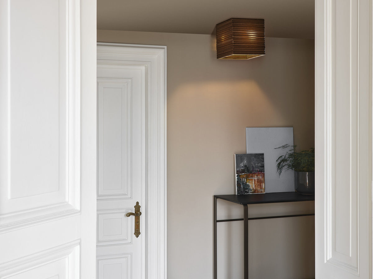 Mise en ambiance dans un couloir clair, plafonnier carré fixé au plafond.