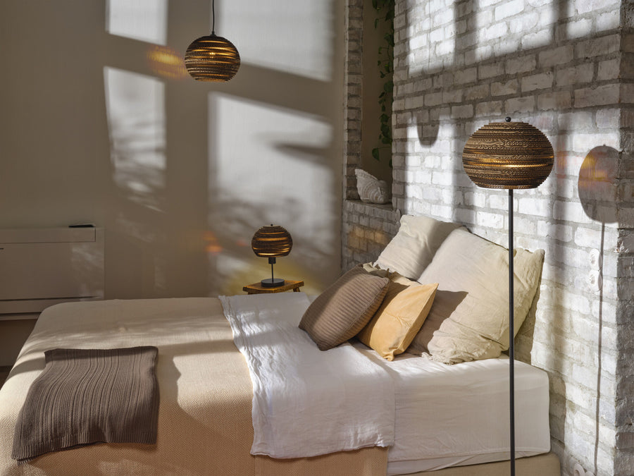 Lampadaire boule dans une chambre lumineuse, avec suspension et lampe de chevet assorties.
