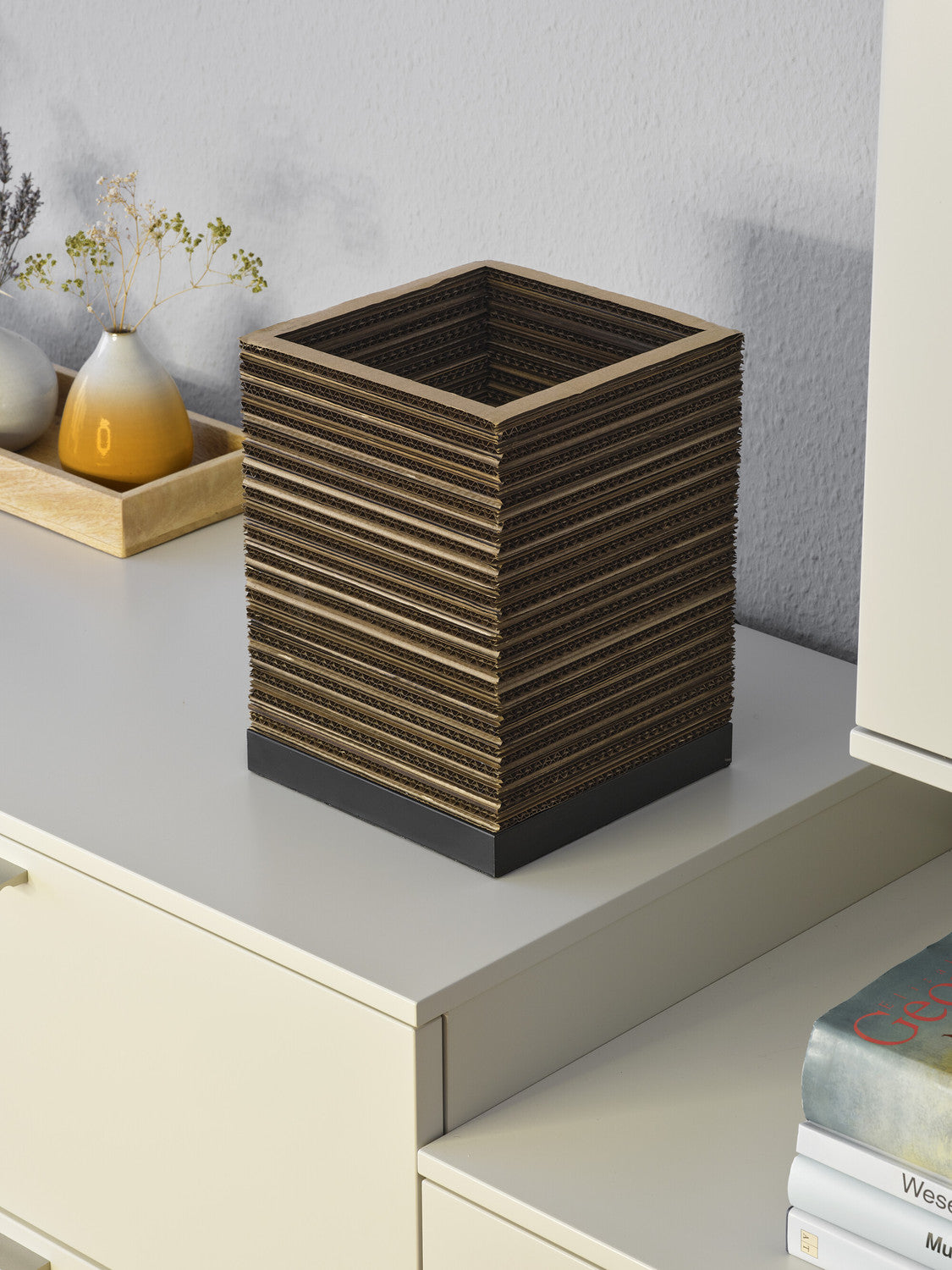 Lampe carrée vue de dessus, posée sur un meuble clair avec un vase jaune.