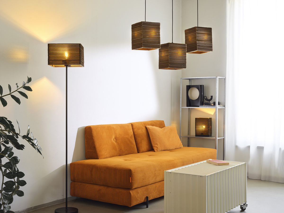 Mise en ambiance avec suspensions, lampadaire et lampe carrée sur une étagère.