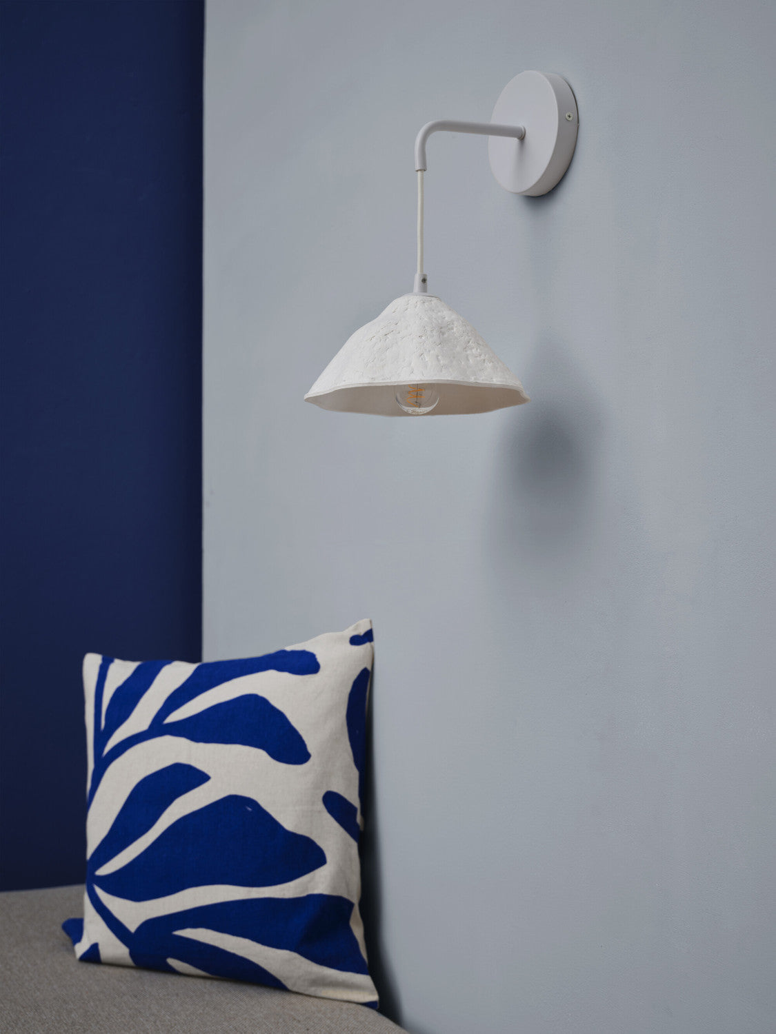 Gros plan du luminaire fixé au mur, ampoule visible sous l'abat-jour
