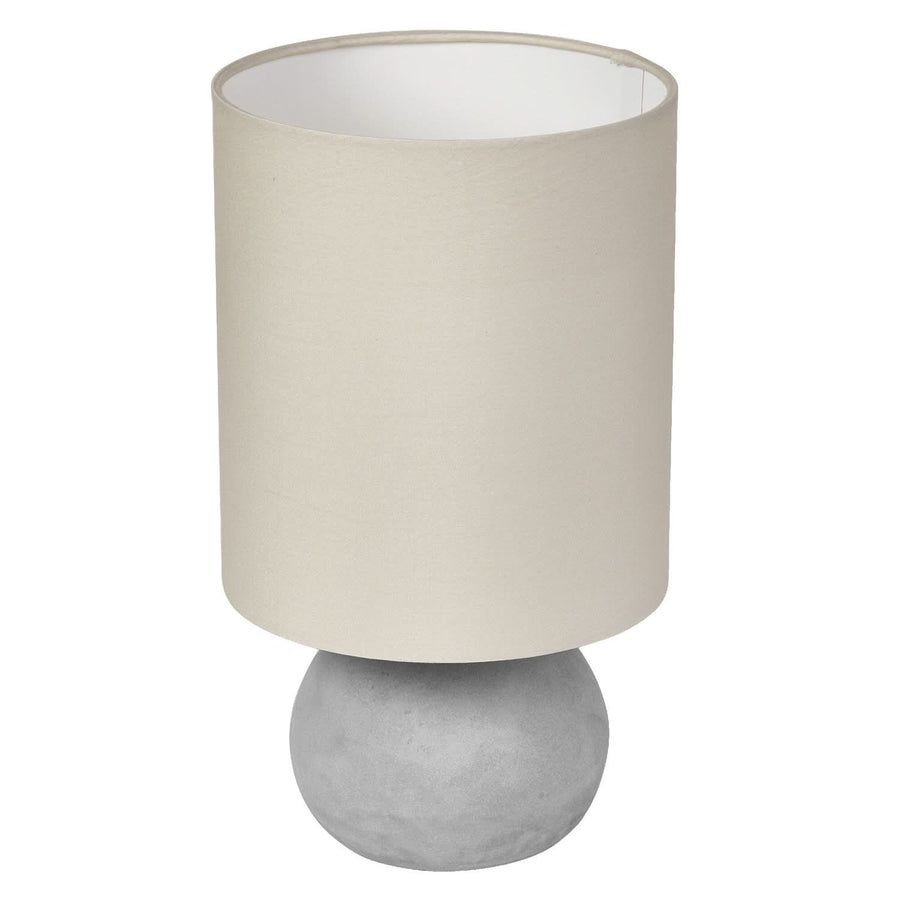 Lampe à poser de face, abat-jour beige cylindrique et base sphérique en béton gris.