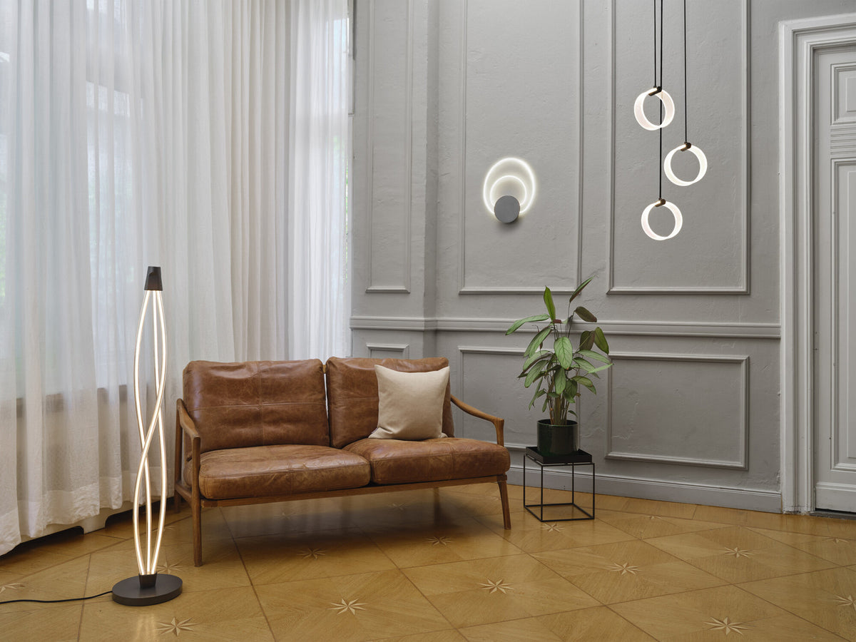 Mise en ambiance salon : lampadaire lumineux près d'un canapé en cuir et rideaux.