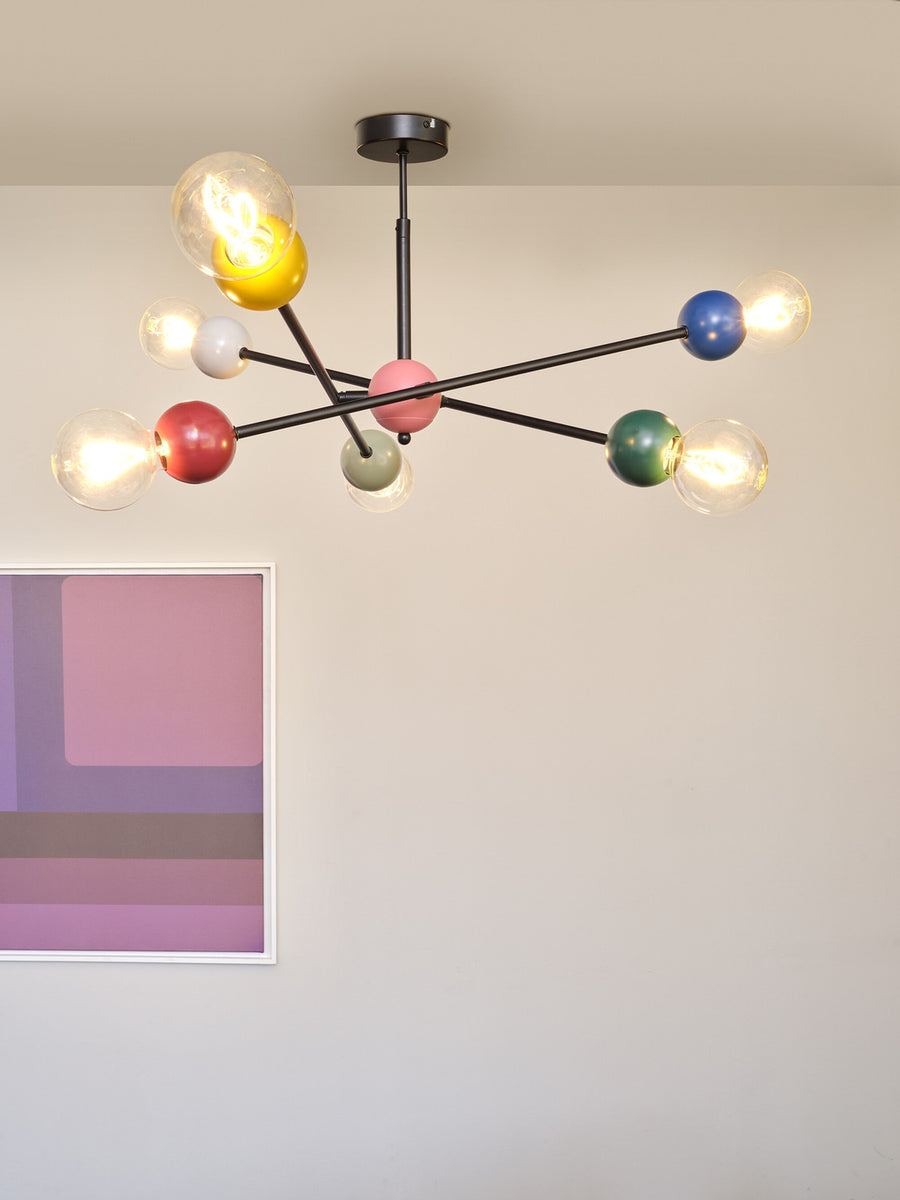 Gros plan sur les globes colorés allumés et les bras noirs du luminaire.