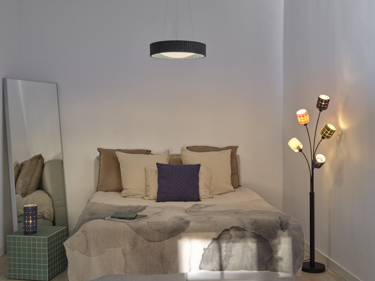 Mise en ambiance dans une chambre claire, suspension allumée au-dessus du lit.