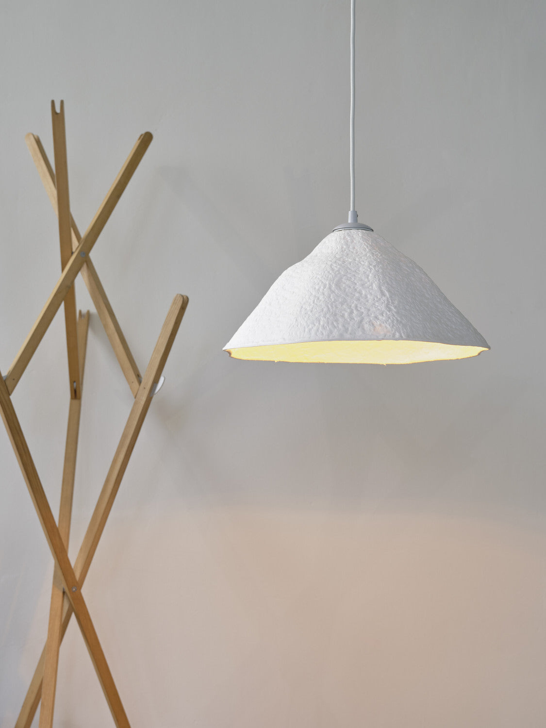 Gros plan sur l'abat-jour allumé, révélant la texture irrégulière et la lumière chaude.