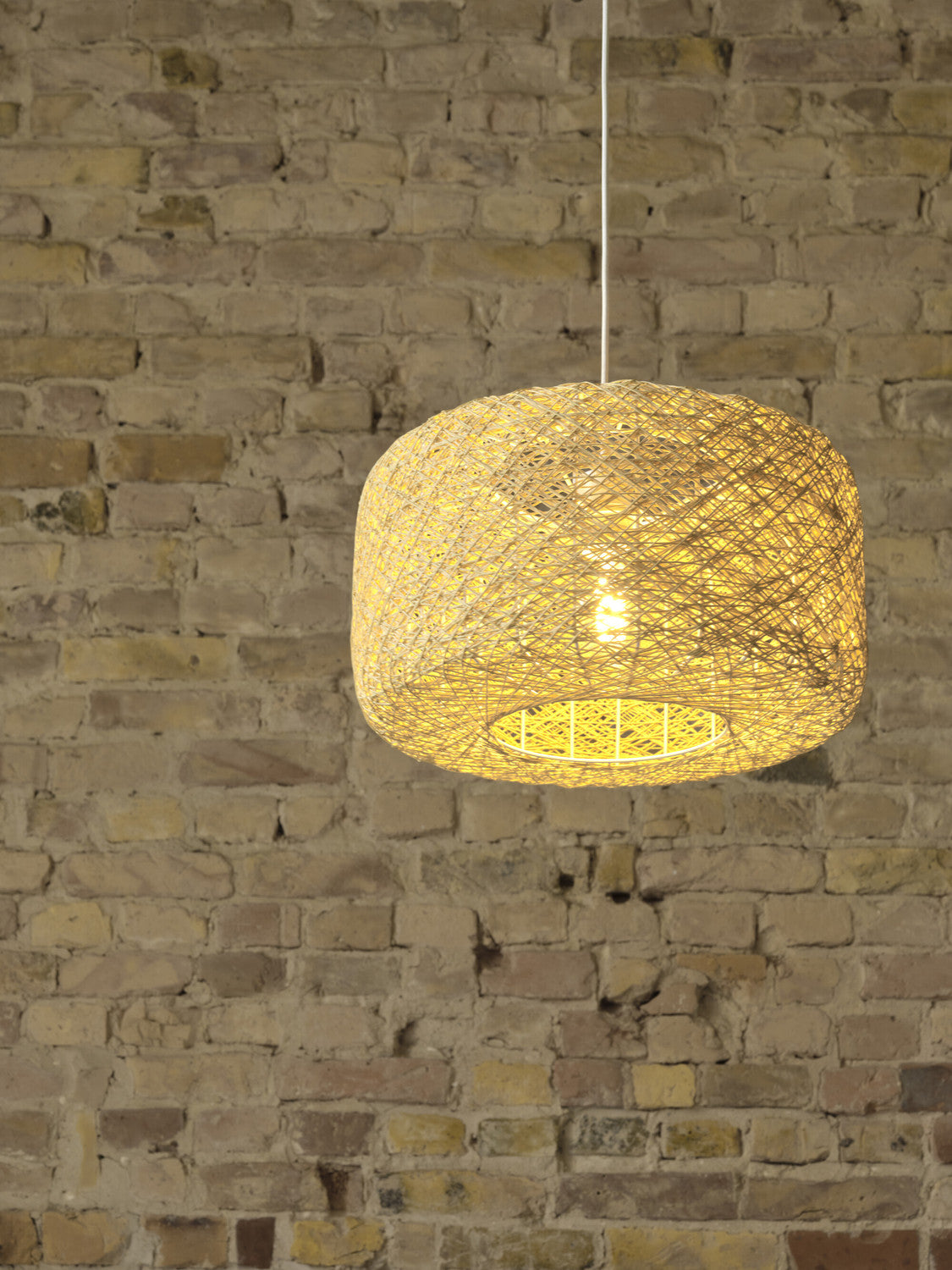 Détail de l’abat-jour lumineux sur fond de mur en briques claires.