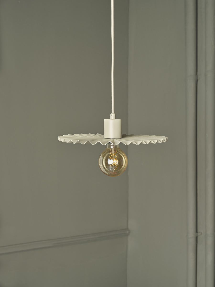 Gros plan sur suspension beige allumée, ampoule globe et abat-jour plissé.