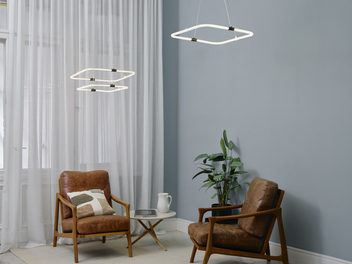 Deux suspensions géométriques illuminant une pièce avec deux fauteuils en cuir.
