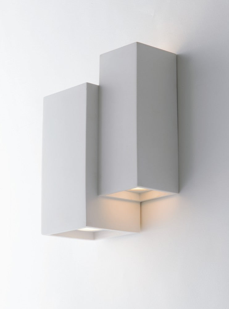Applique murale installée sur un mur blanc, deux boîtiers rectangulaires éclairant vers le bas.