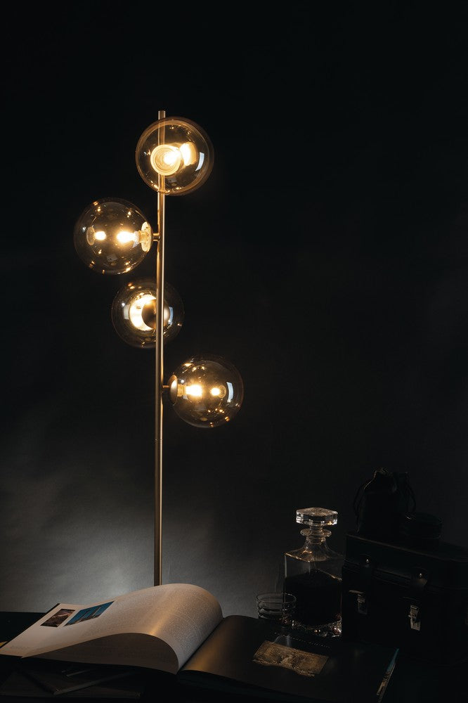Mise en ambiance nocturne, lampadaire allumé éclairant un livre ouvert et une carafe.