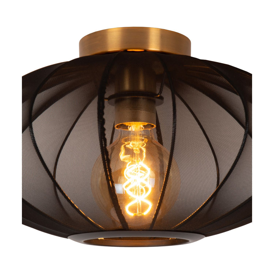 Gros plan sur l'abat-jour en tissu noir et l'ampoule filament dorée qui diffuse une lumière chaude
