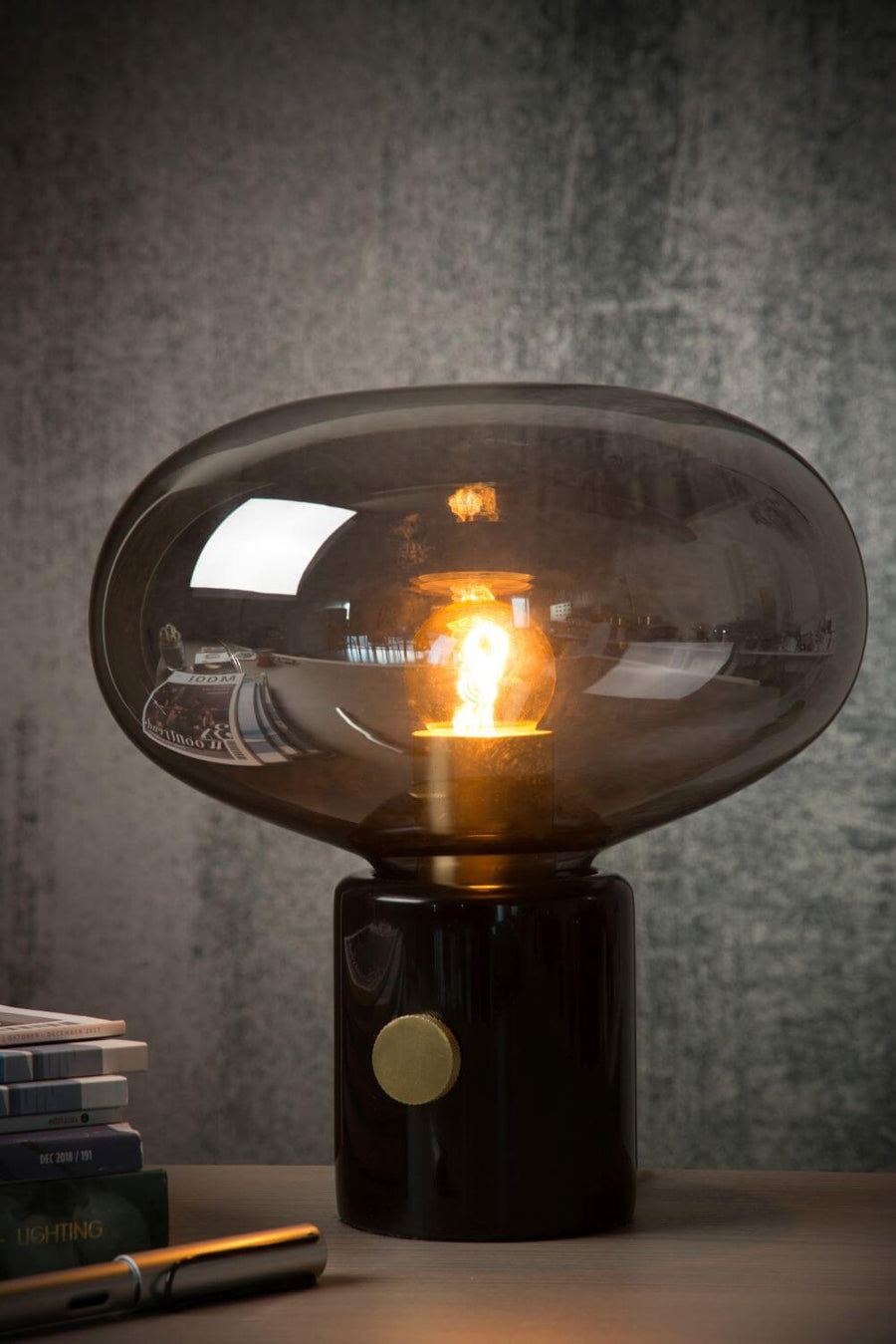 Gros plan de face révélant l'ampoule dorée dans le verre fumé transparent.