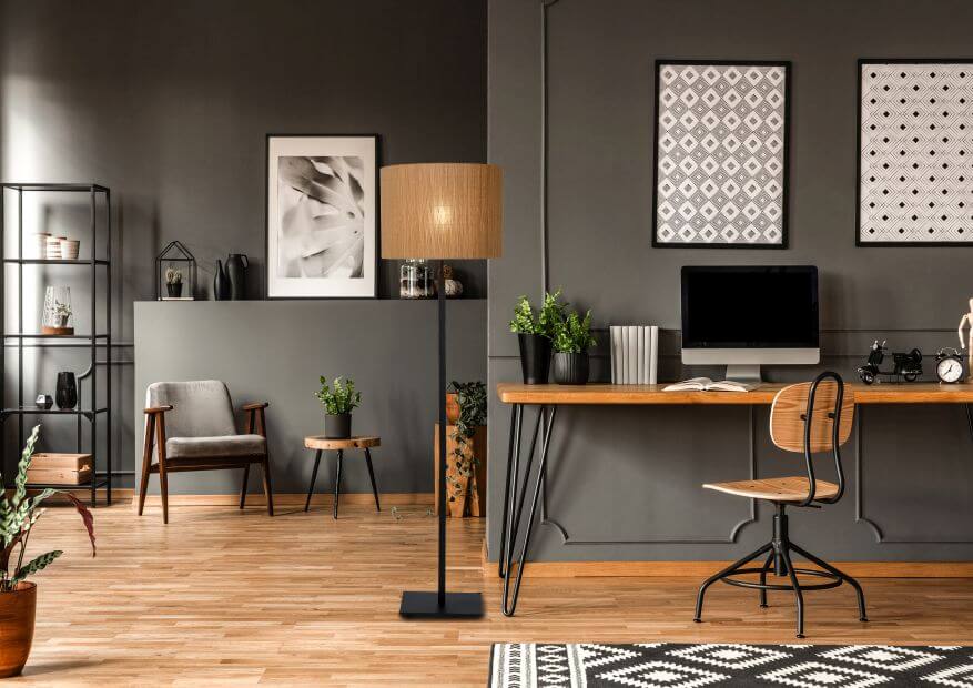 Mise en ambiance d'un bureau avec lampadaire allumé derrière un écran et des cadres.