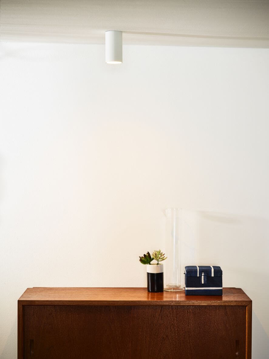 Plafonnier cylindrique blanc installé au plafond au-dessus d'un meuble en bois