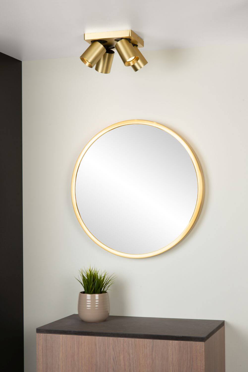 Vue rapprochée du luminaire doré et de son reflet dans le miroir rond