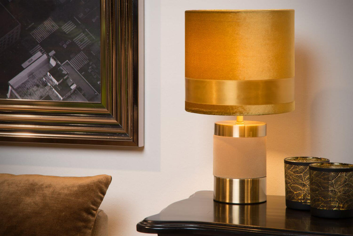 Gros plan sur l'abat-jour doré et le pied cylindrique de la lampe à poser
