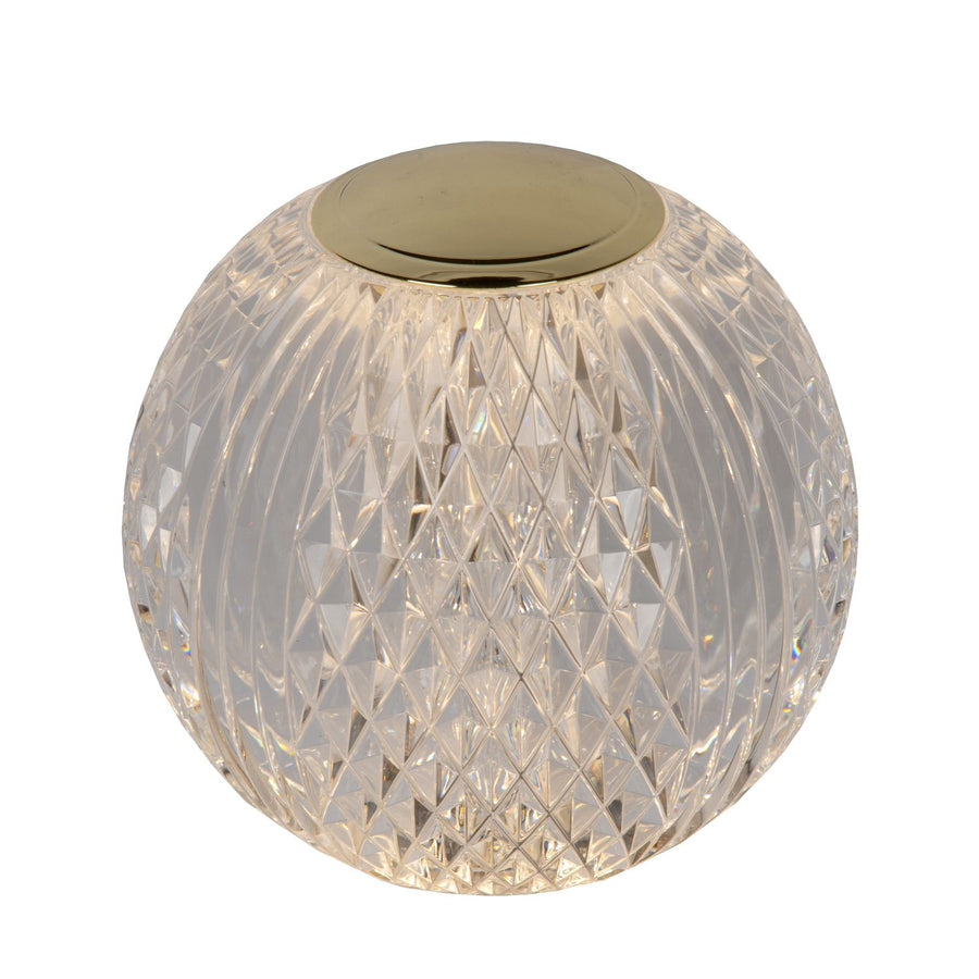 Lampe à poser en verre transparent facetté, capuchon doré, vue de trois quarts sur fond blanc.