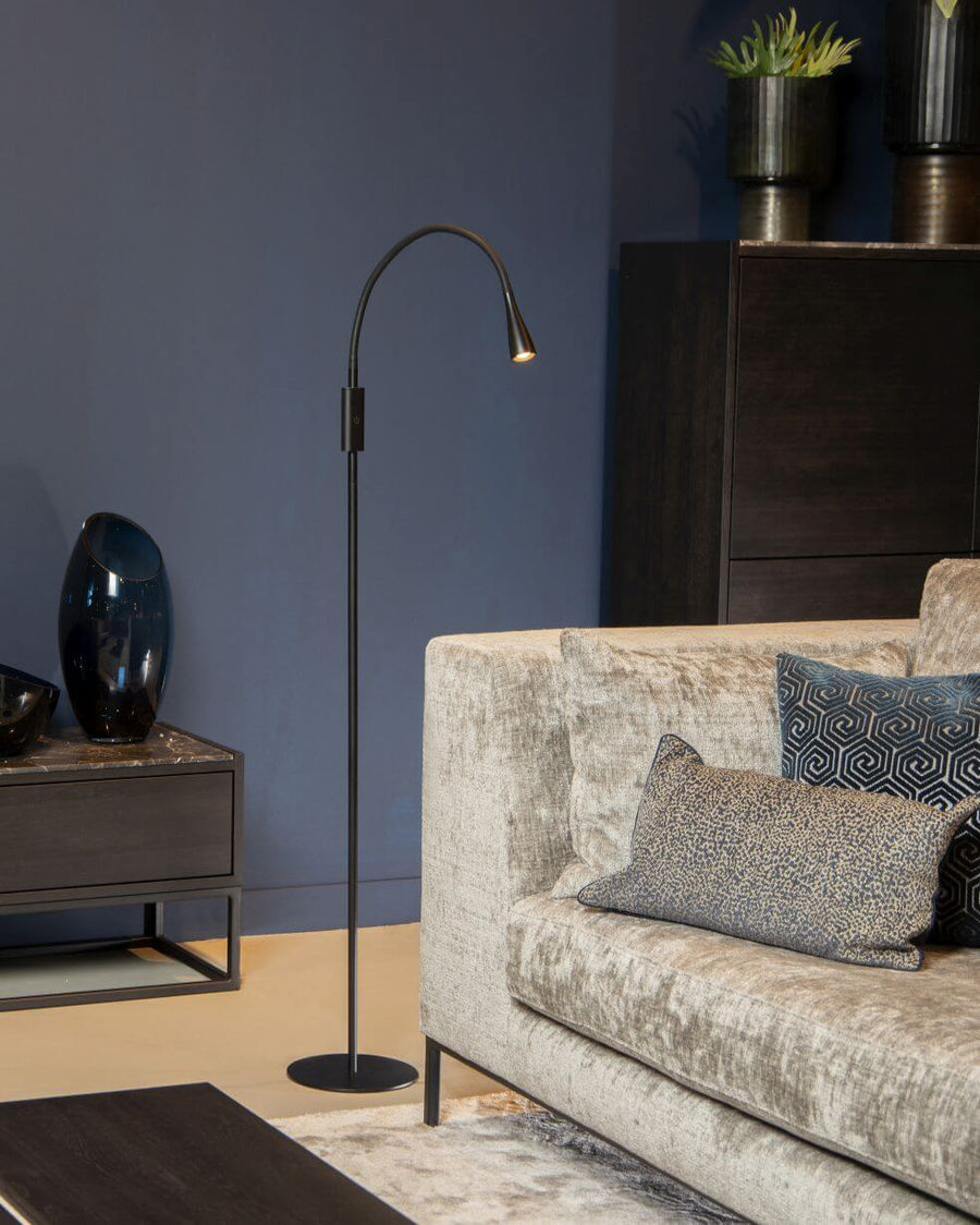 Lampadaire noir dressé dans un salon moderne près d'un canapé beige et d'un meuble sombre