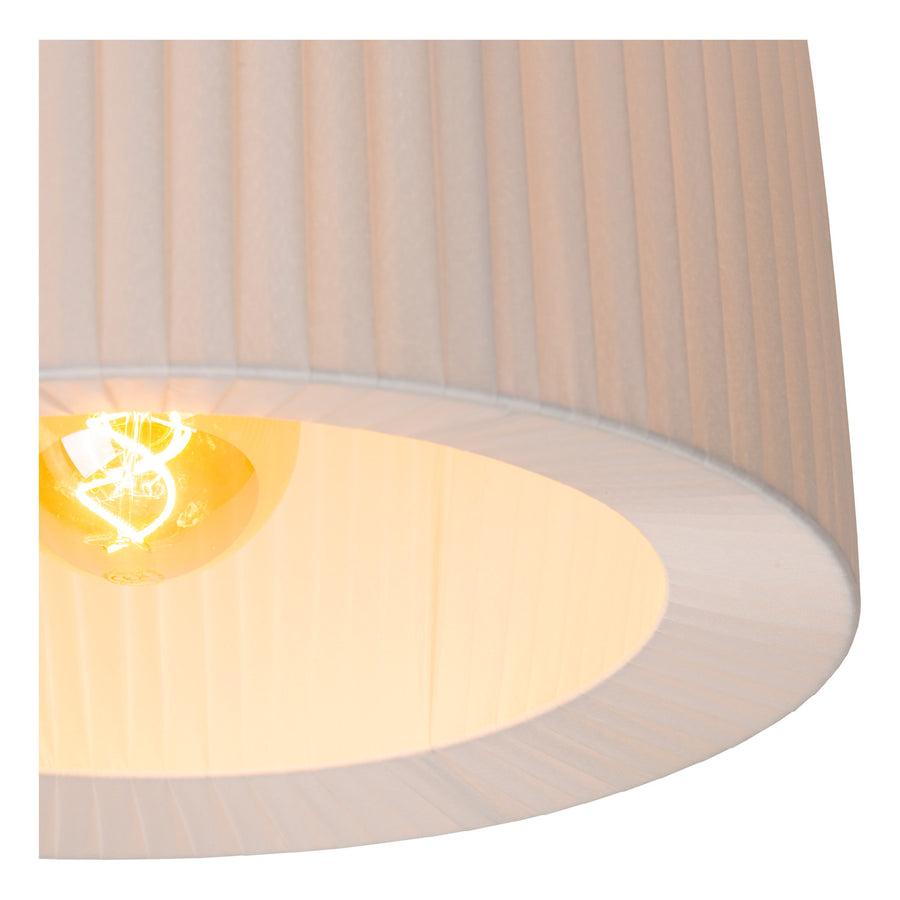 Détail de l'intérieur du plafonnier, ampoule allumée et plis du tissu blanc.