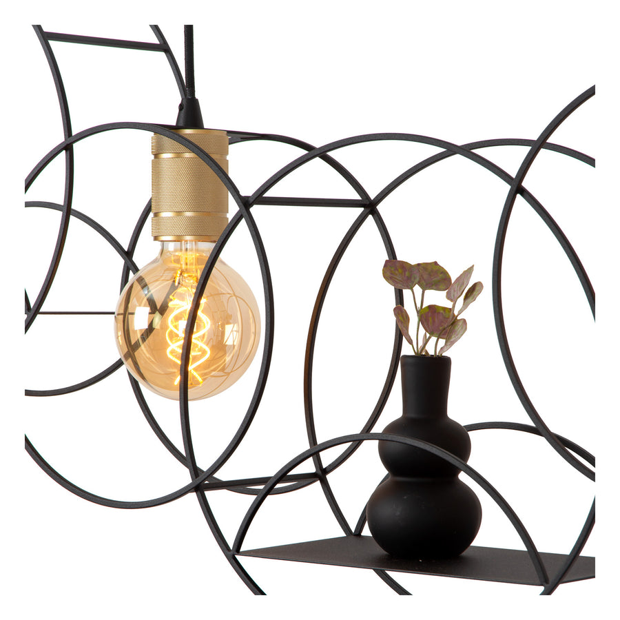 Détail d'une ampoule sur douille dorée, cercles noirs et petit vase avec plante.