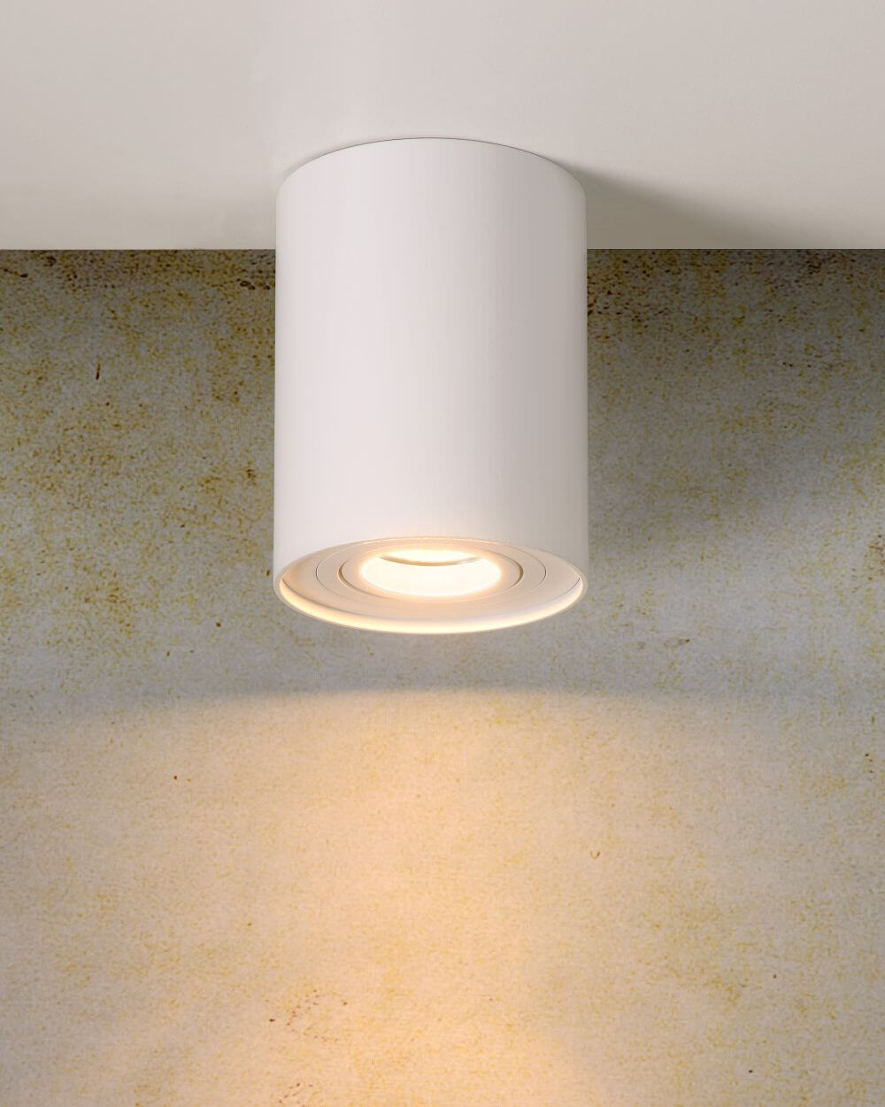 Gros plan du plafonnier blanc allumé, éclairant un mur texturé beige.