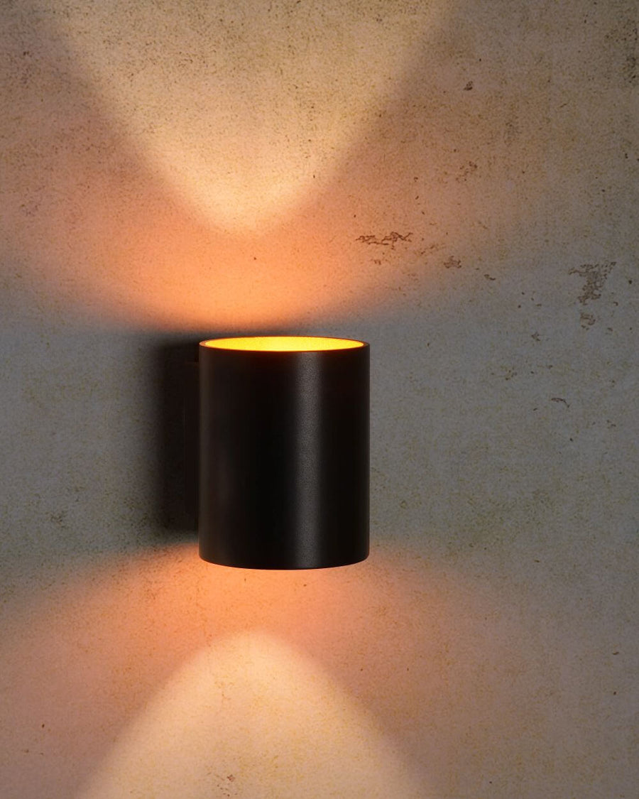 Effet lumineux chaud de l'applique noire sur un mur en béton brut