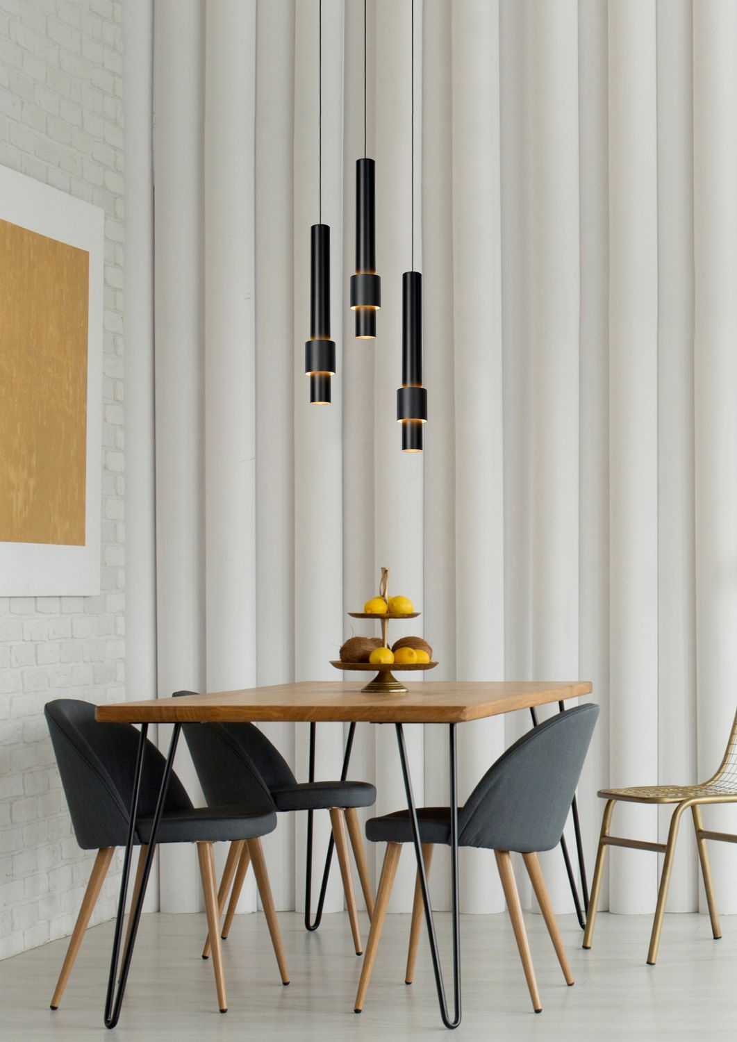 Vue rapprochée des trois cylindres noirs suspendus diffusant une lumière dorée