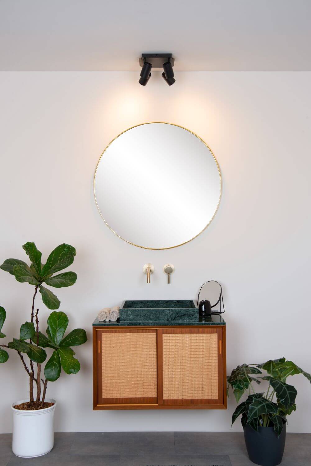 Vue rapprochée du luminaire au plafond surmontant un meuble vasque en rotin