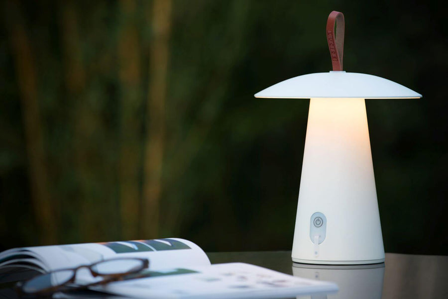 Vue rapprochée de la lampe blanche allumée, détail de l'abat-jour rond et du socle conique.