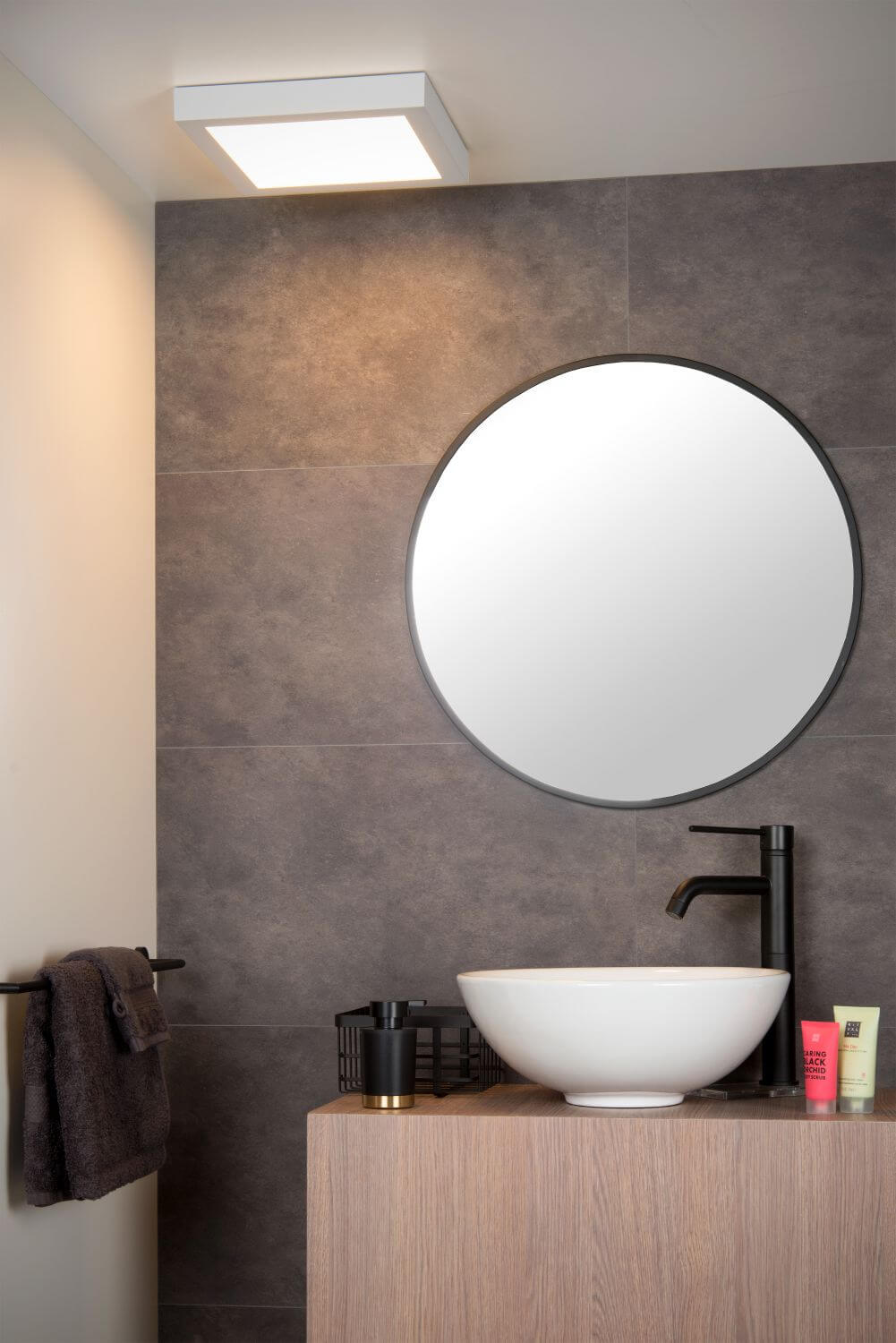 Mise en ambiance salle de bain : luminaire carré éclairant le mur au-dessus du lavabo