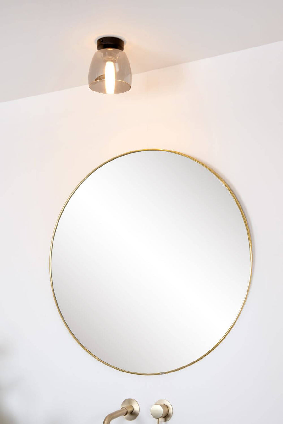 Contre-plongée du luminaire allumé diffusant un halo chaud sur le mur