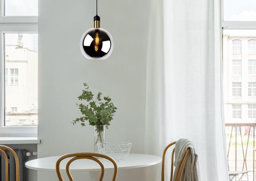 Vue rapprochée du globe en verre fumé suspendu, ampoule dorée visible à l'intérieur