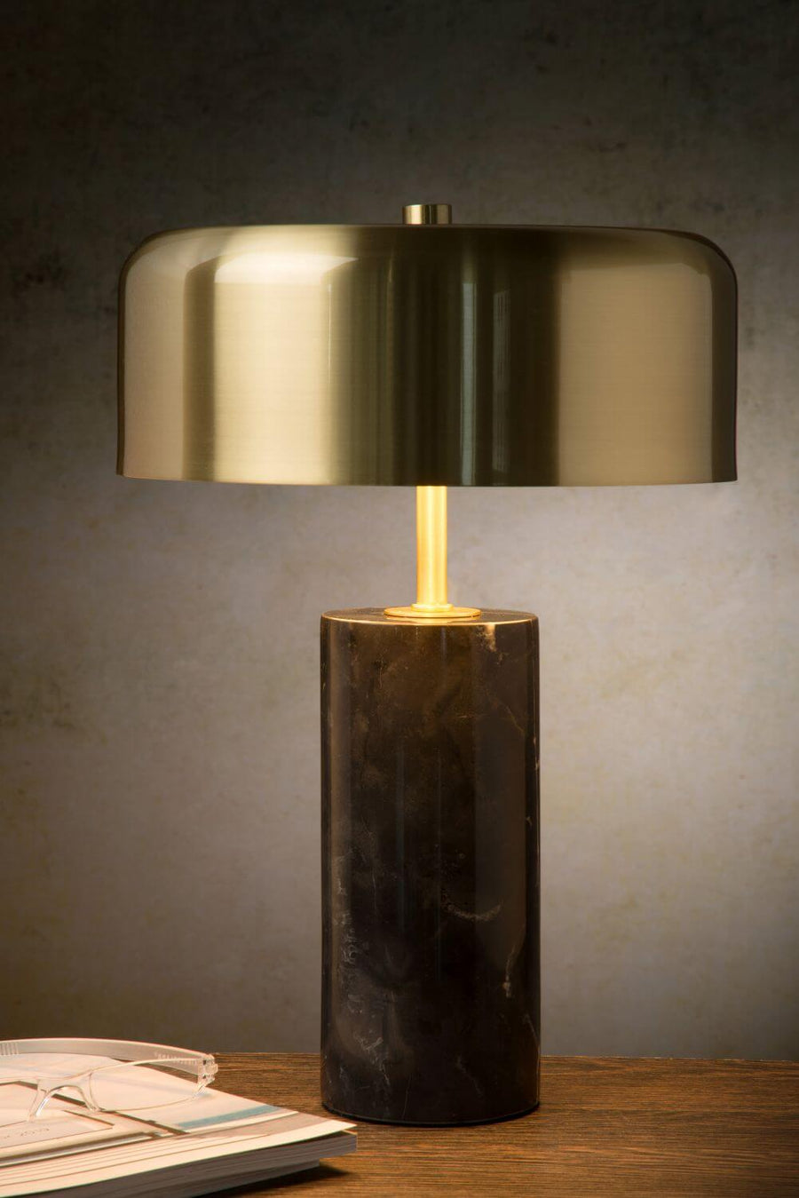 Vue rapprochée du luminaire allumé, abat-jour doré et socle cylindrique en marbre