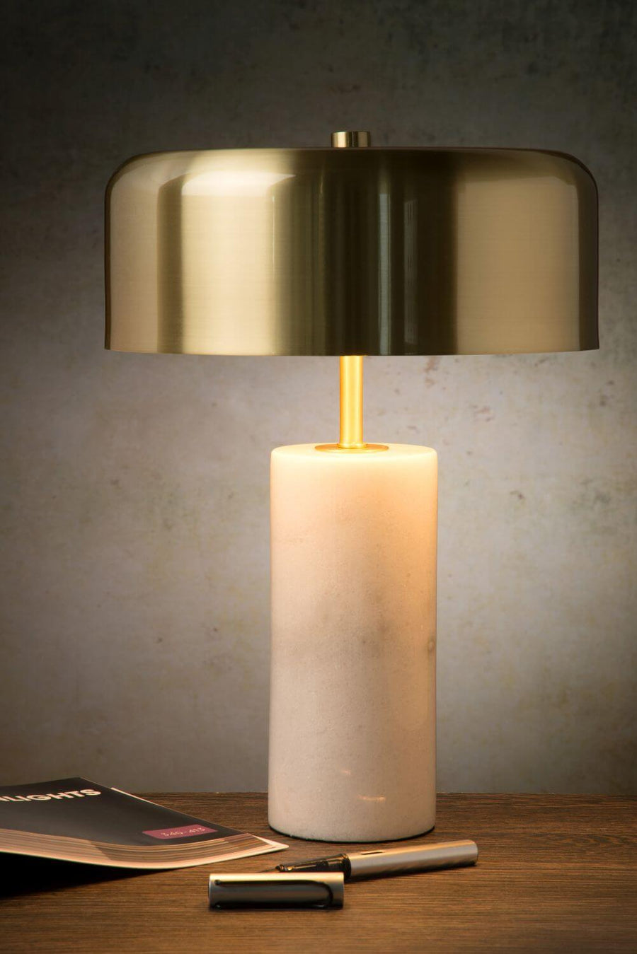 Vue rapprochée de la lampe allumée, mettant en valeur le marbre et le laiton.