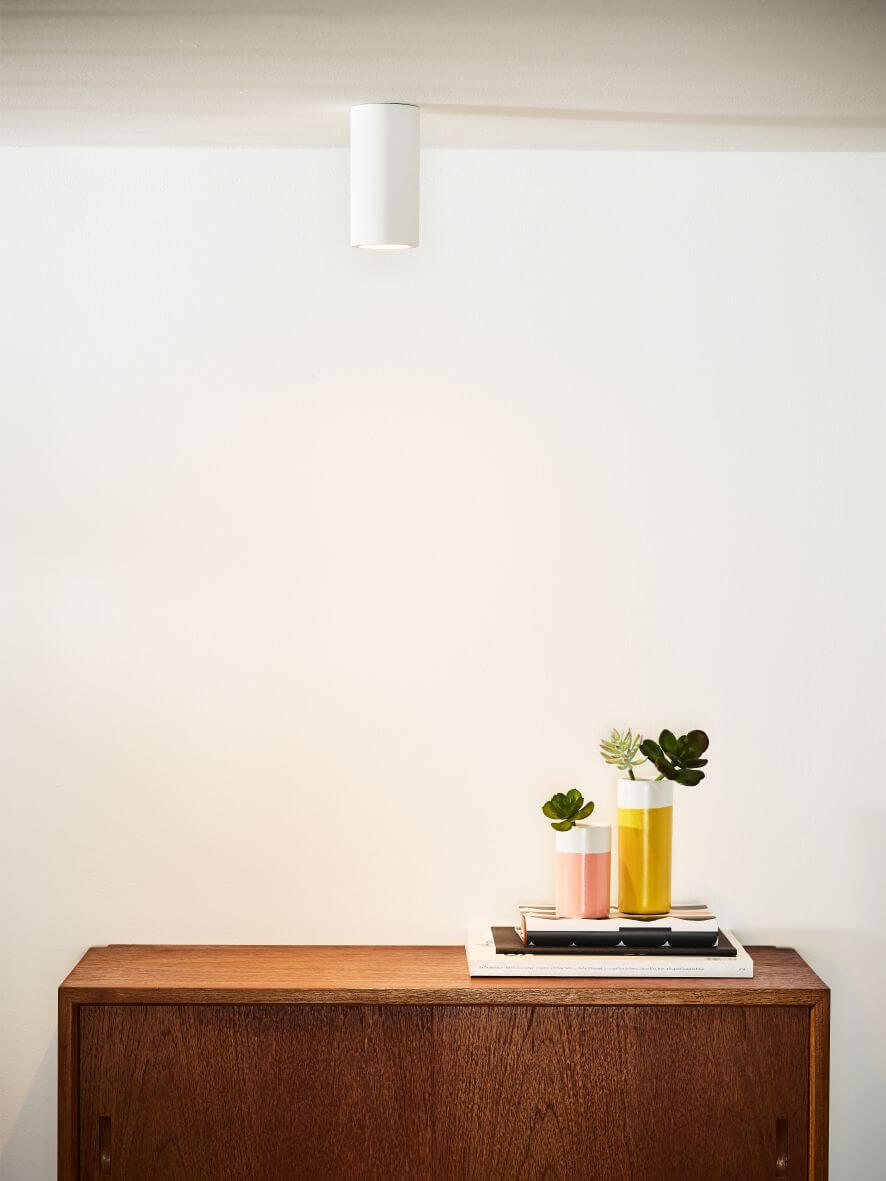 Plafonnier cylindrique blanc fixé au plafond au-dessus d'un meuble en bois
