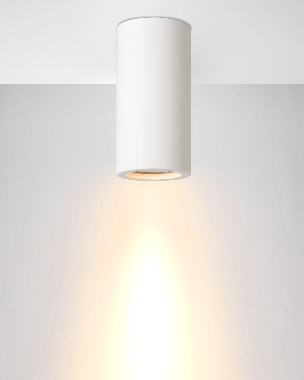 Plafonnier blanc au plafond, halo de lumière chaude vers le bas