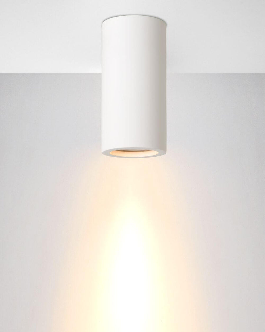 Plafonnier blanc au plafond, halo de lumière chaude vers le bas