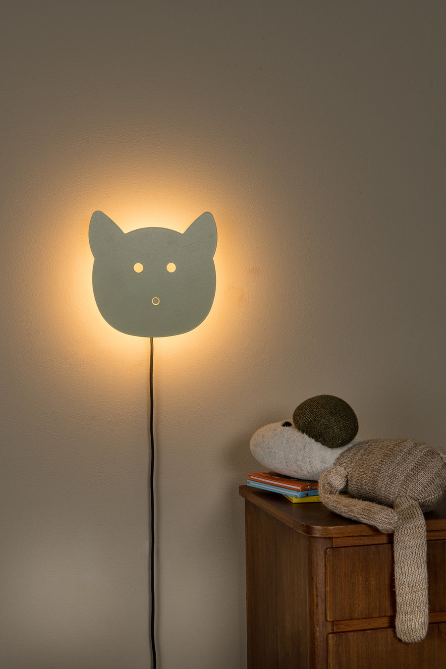 Vue complète de l'applique murale verte lumineuse fixée au mur au-dessus d'une commode.