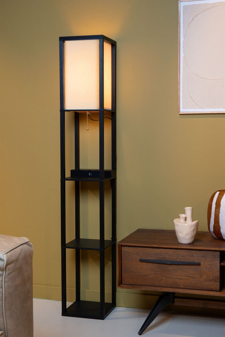 Vue de face du lampadaire allumé, posé contre le mur près d'une commode