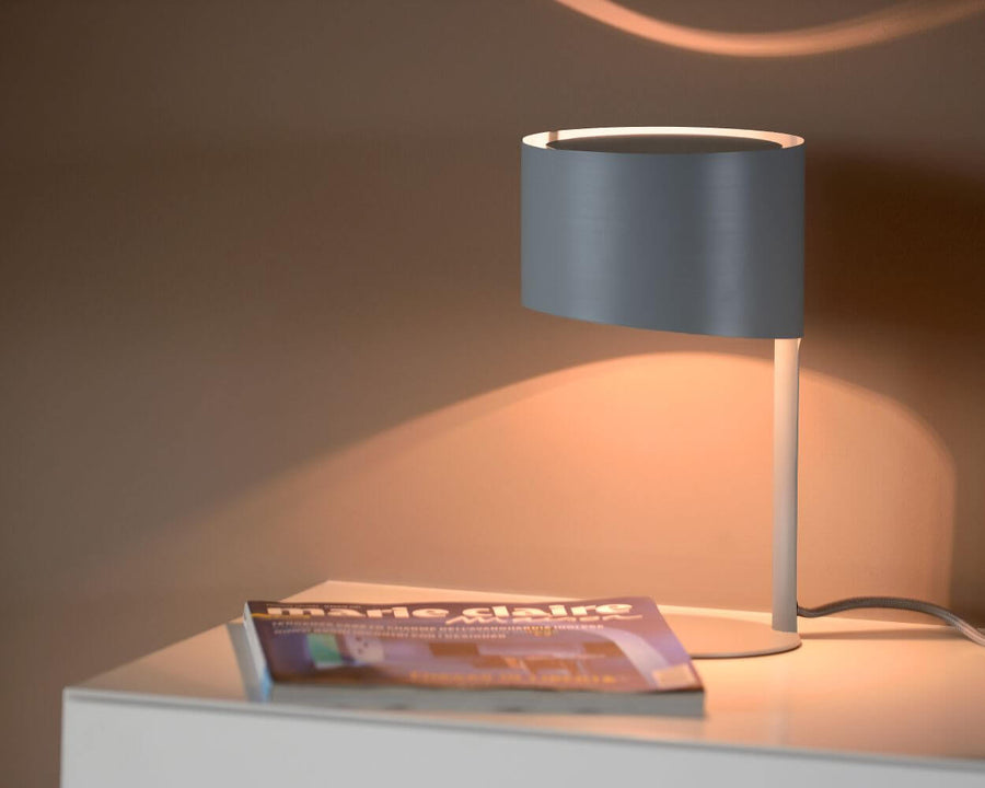 Lampe à poser allumée posée sur une table avec magazine Marie Claire