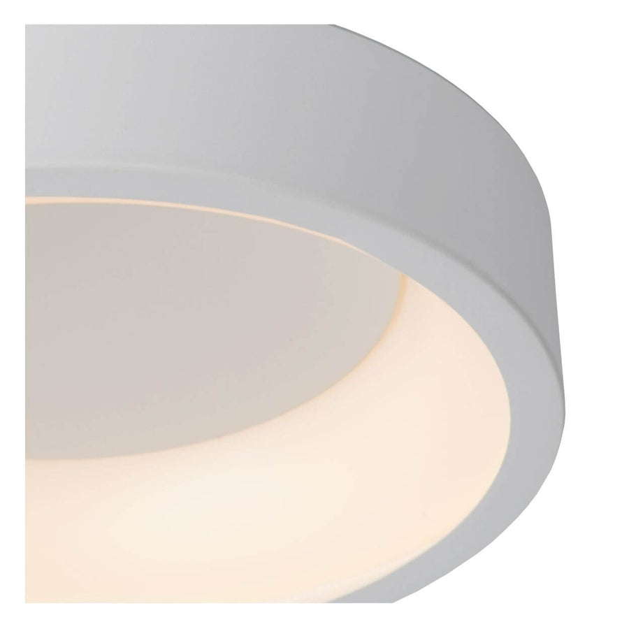 Gros plan sur le bord arrondi et la finition blanche du luminaire allumé
