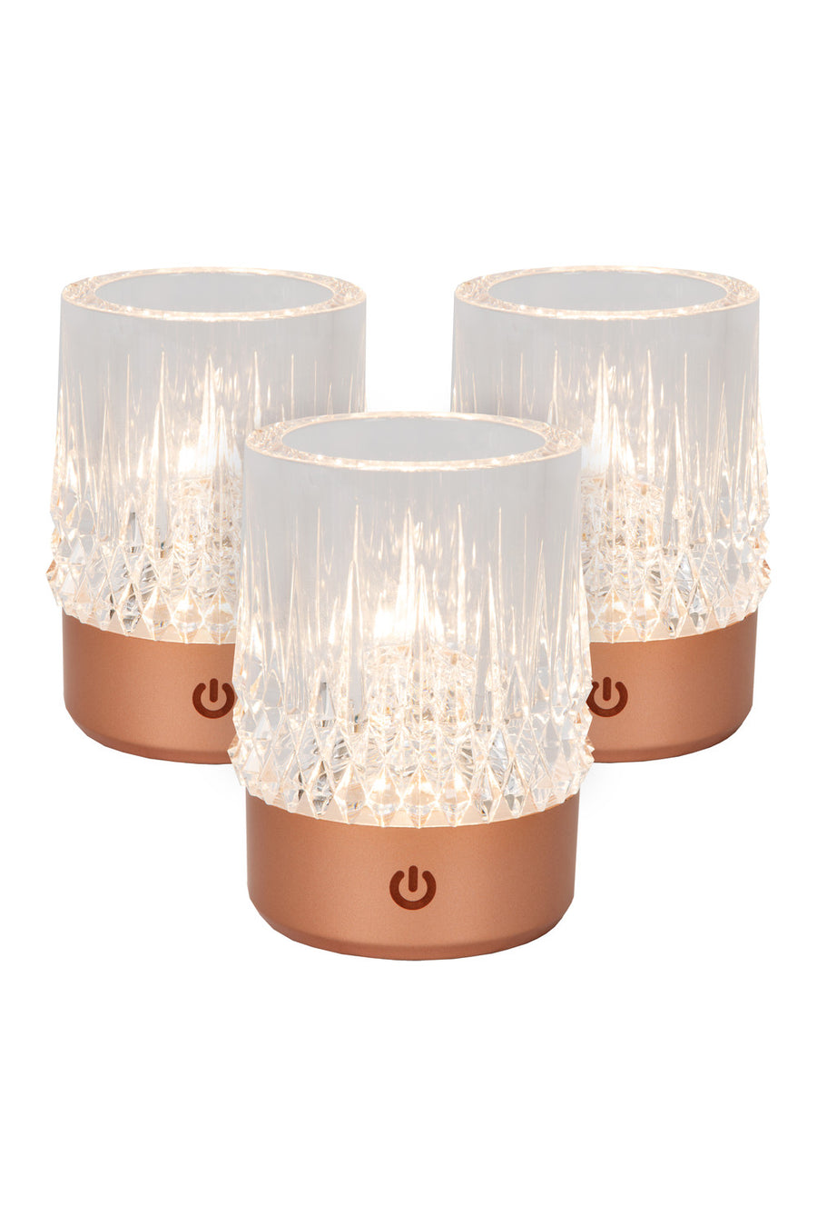 Trois lampes à poser cylindriques cuivrées présentées de face sur fond blanc, éclairées.